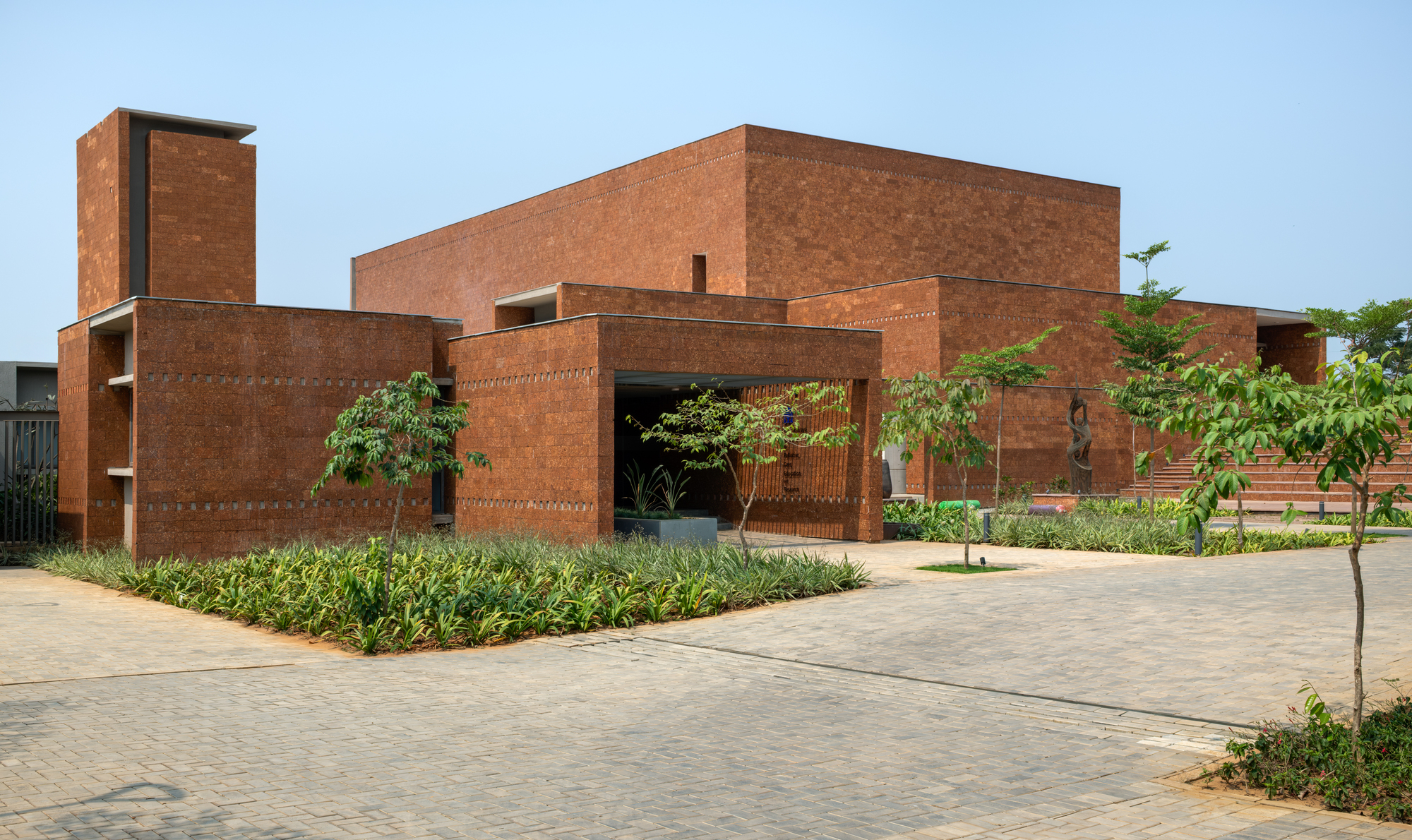Administrative block with laterite walls, a raised stair volume and a shaded entrance portico