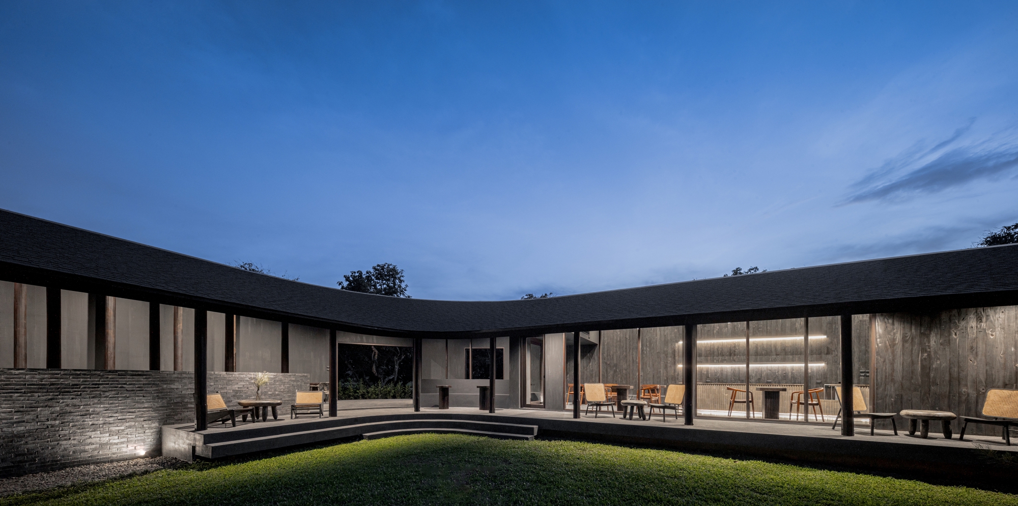 Dusk view across the central grass courtyard to the illuminated cafe dining room
