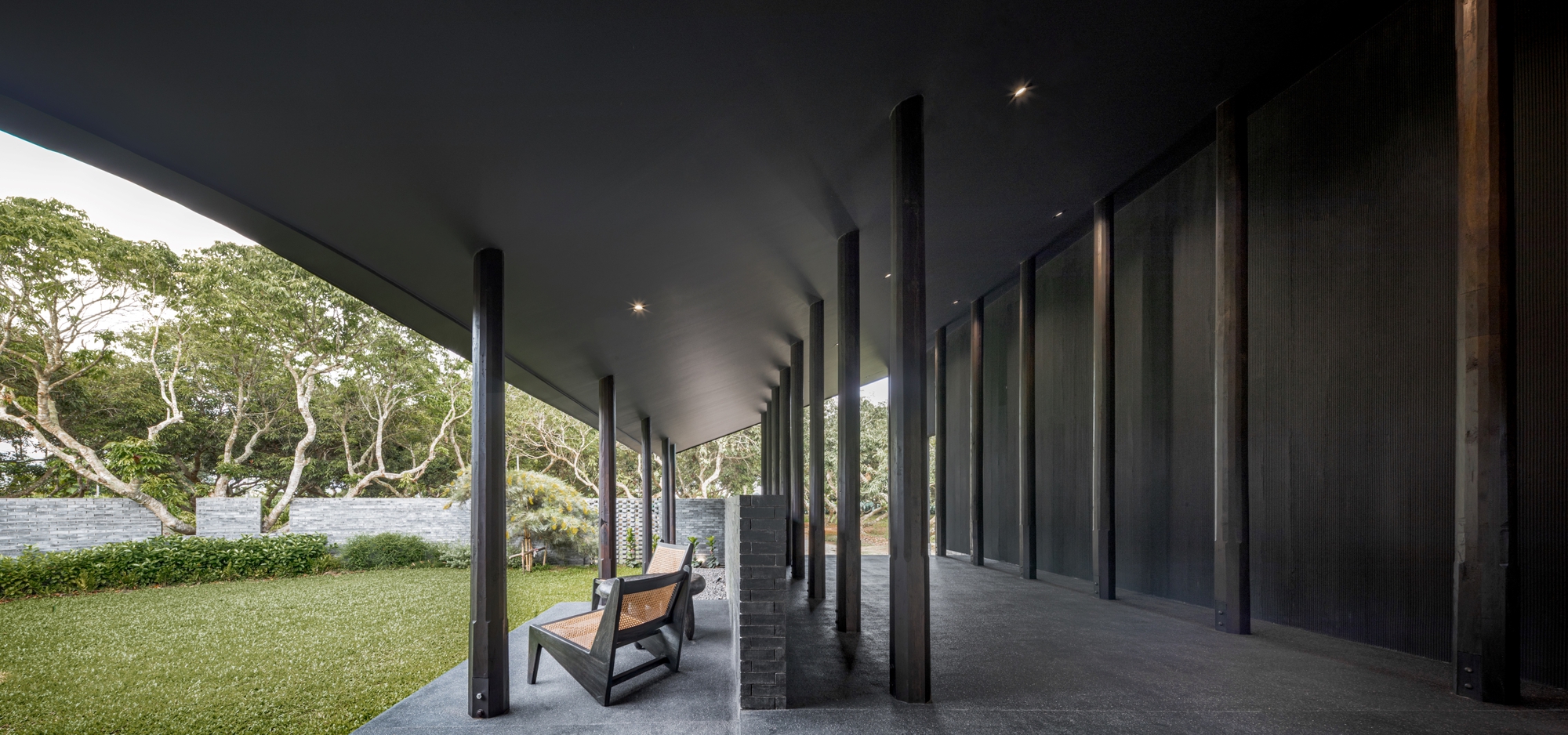 Covered terrace with timber chairs and views out to the garden and an existing tree