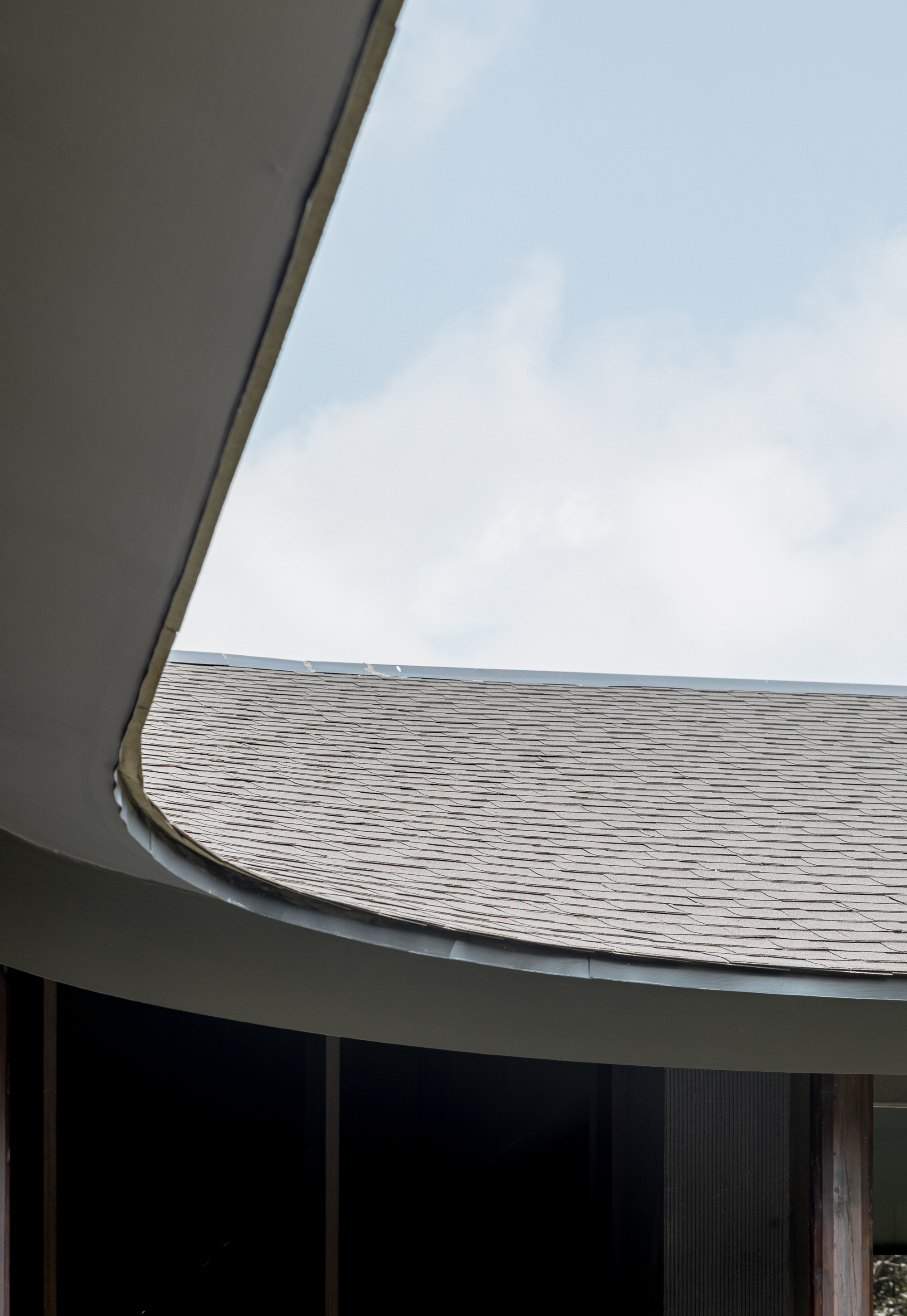 Looking up at a curved folded roof edge meeting the tiled pitched roof