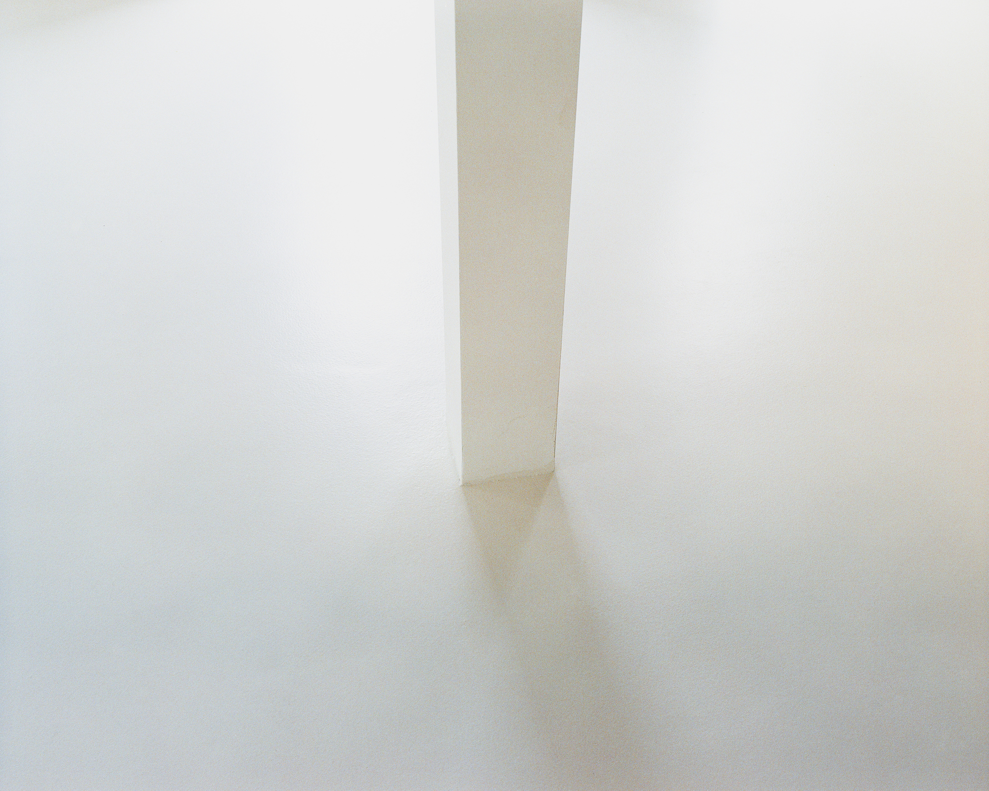 Detail of the slim white pillar standing on the polished concrete floor