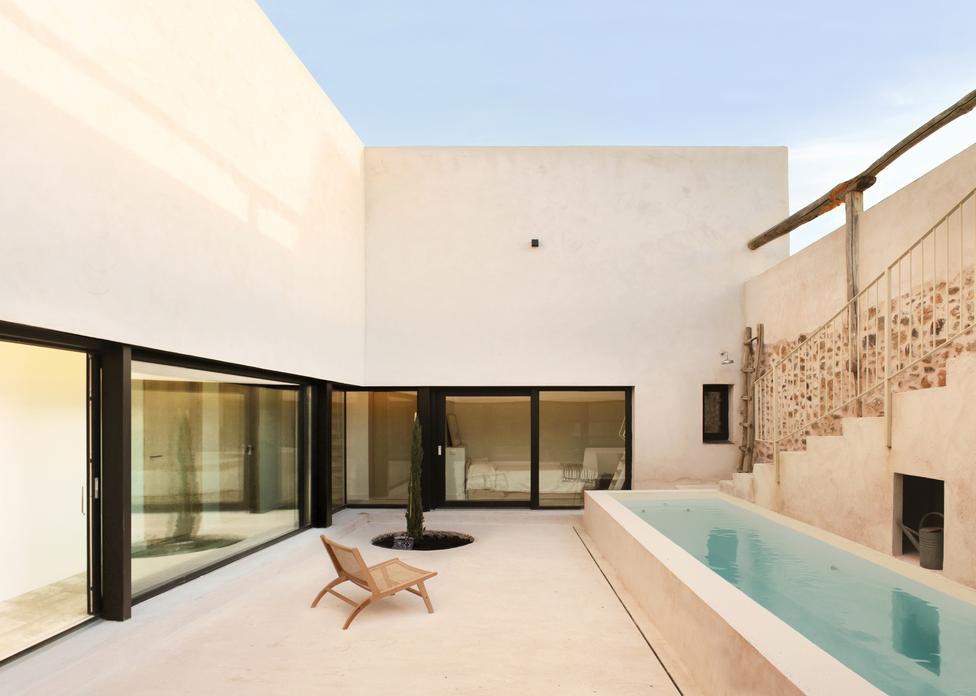 Inner courtyard with the lap pool, a folding chair and a single planted tree