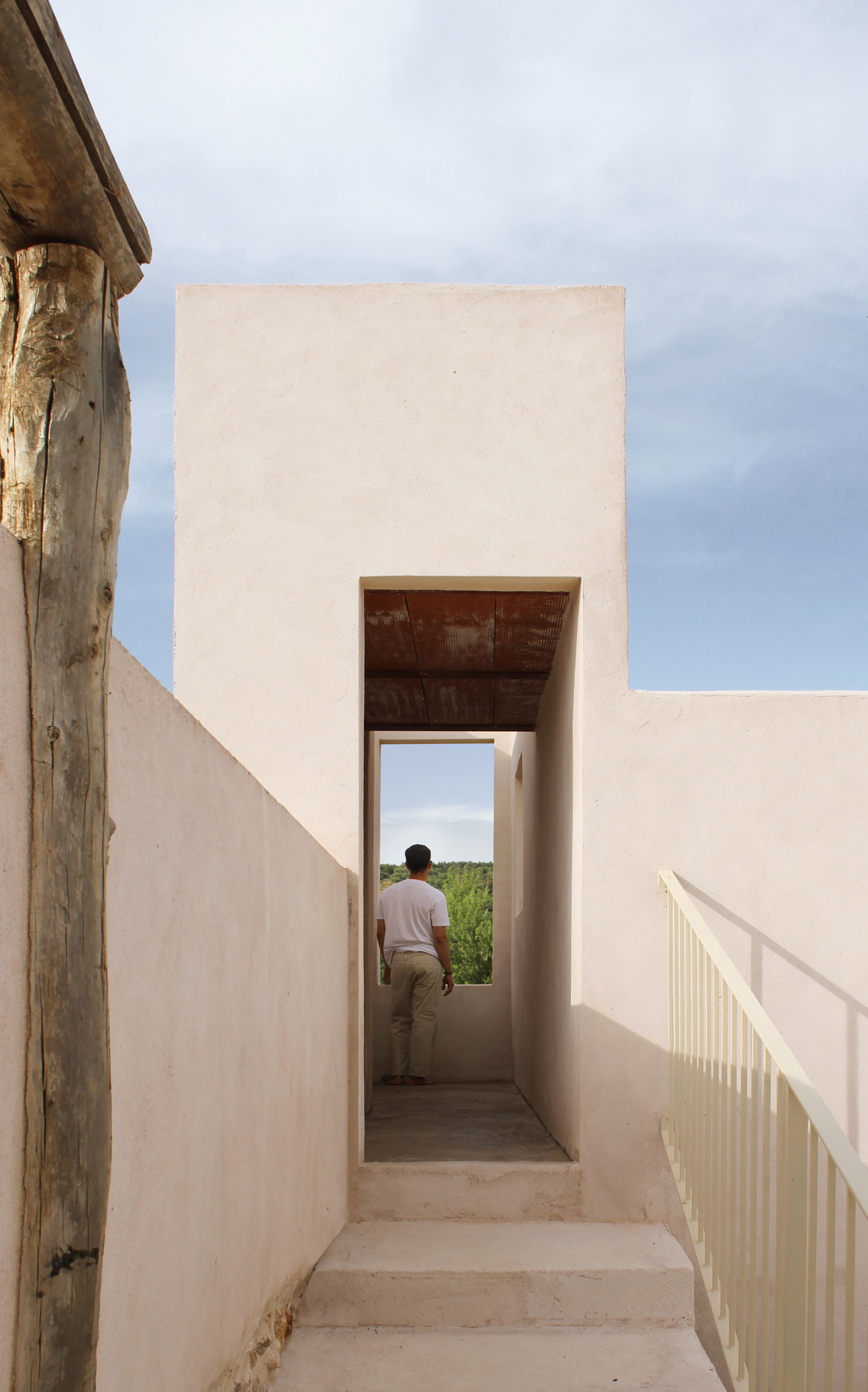 Stair onto the roof terrace passing through a portal cut into the white plaster wall