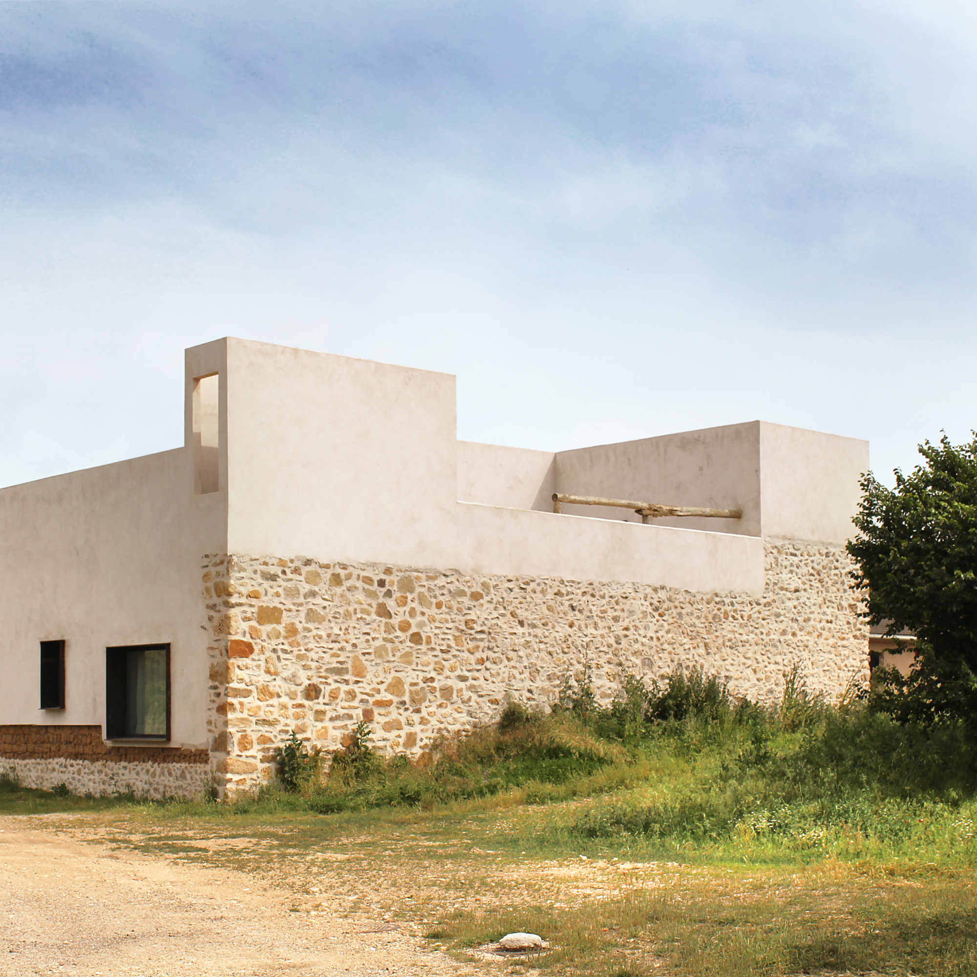 Side view of the house showing the new plaster volume above the original stone enclosure