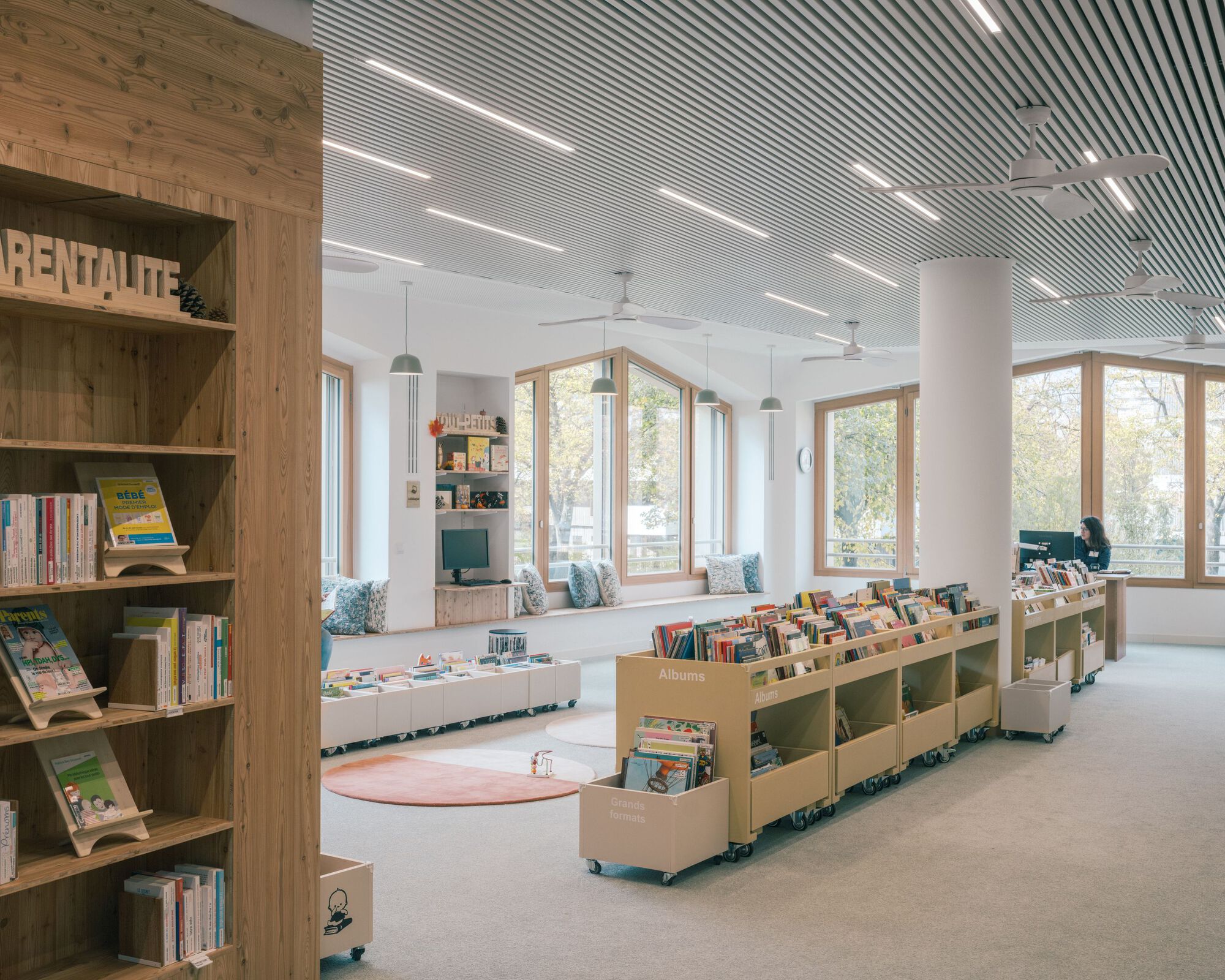 Children's section of the media library with timber bookshelves, gabled reading alcove and a perforated metal ceiling