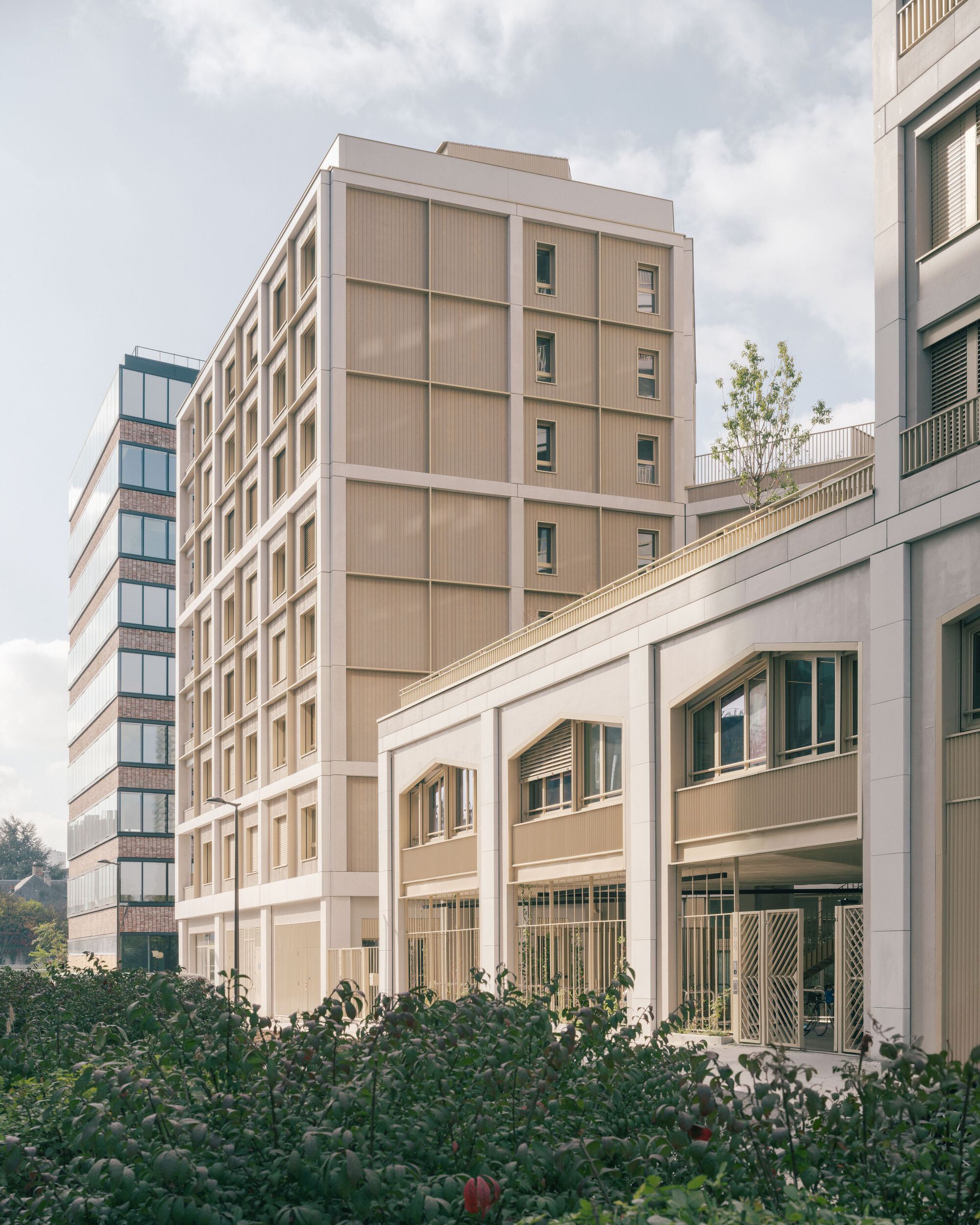Beige and brick facades of two new buildings with the rounded media library volume in the foreground
