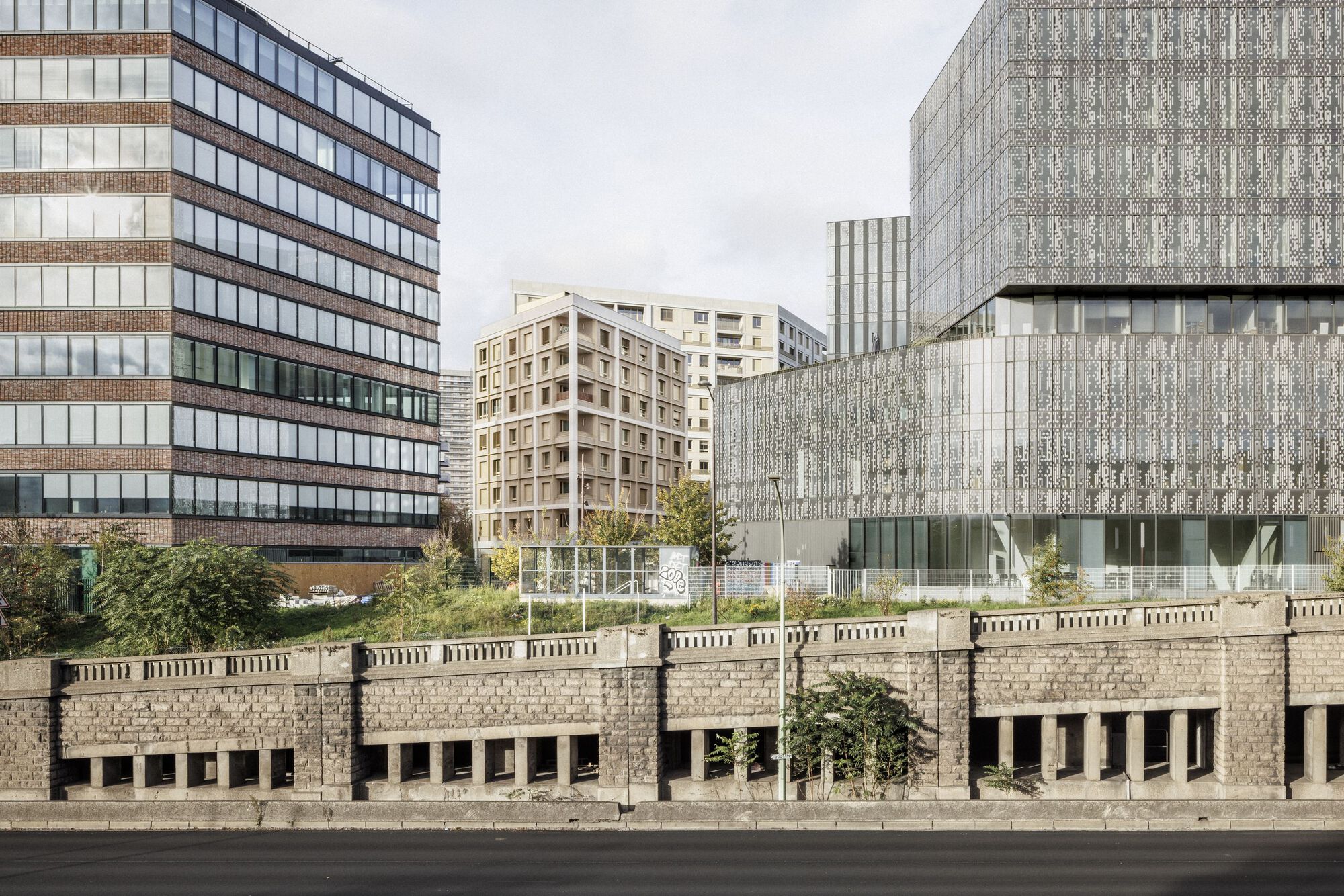 Wider city view showing the media library's perforated metal facade behind the boulevard wall
