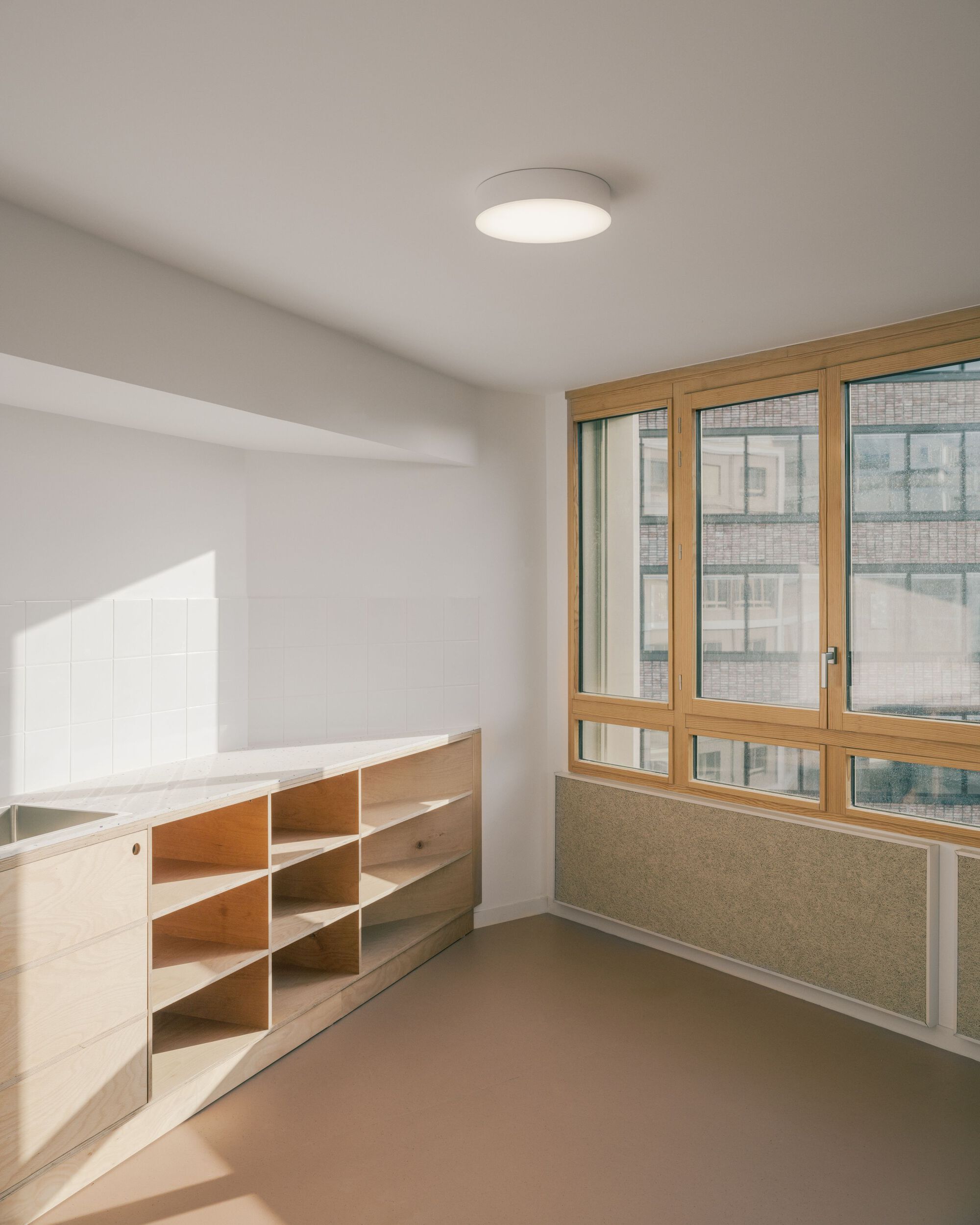 Compact student kitchen unit with a timber base and ground floor view to the neighbouring building