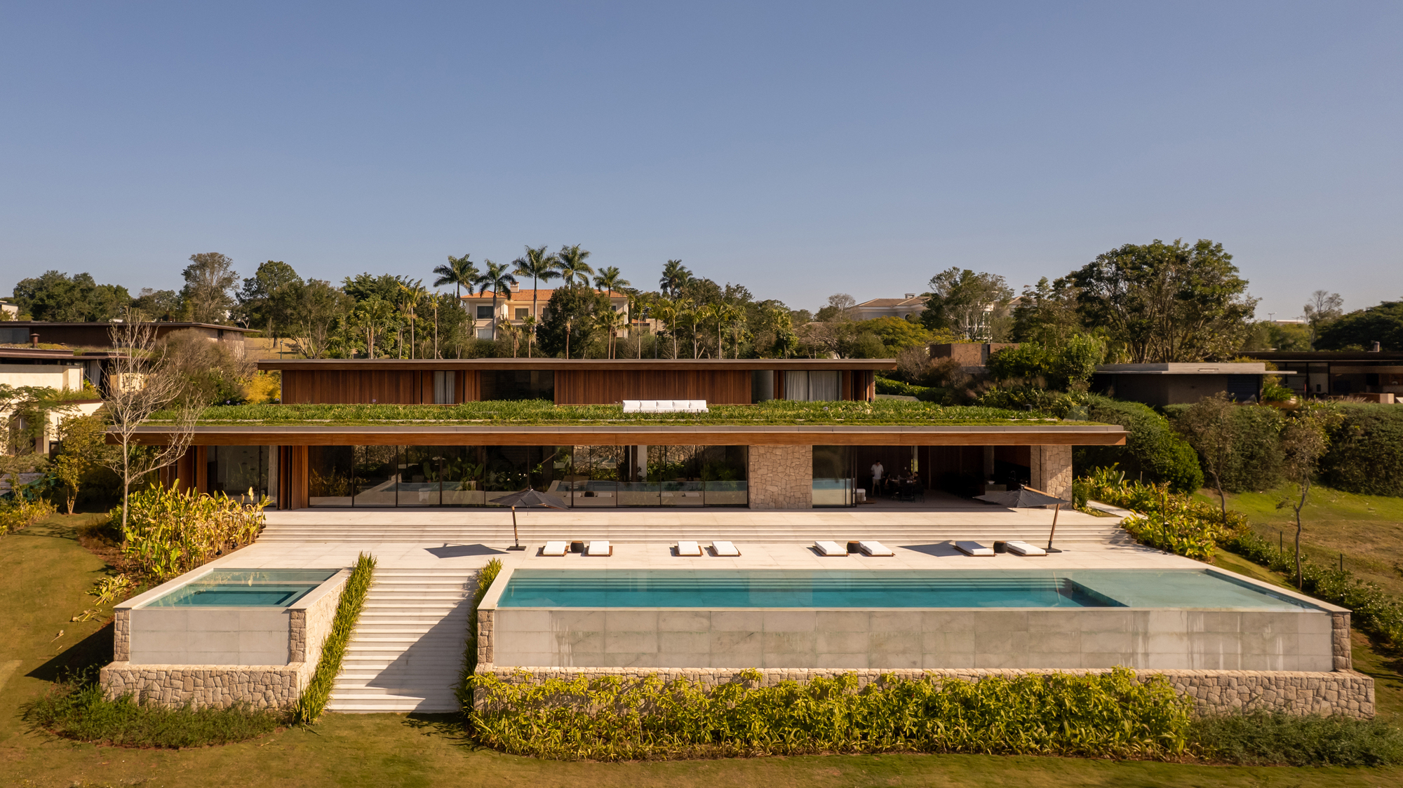 Long elevation of the house seen from across the garden with the lap pool and a small plunge pool in the foreground