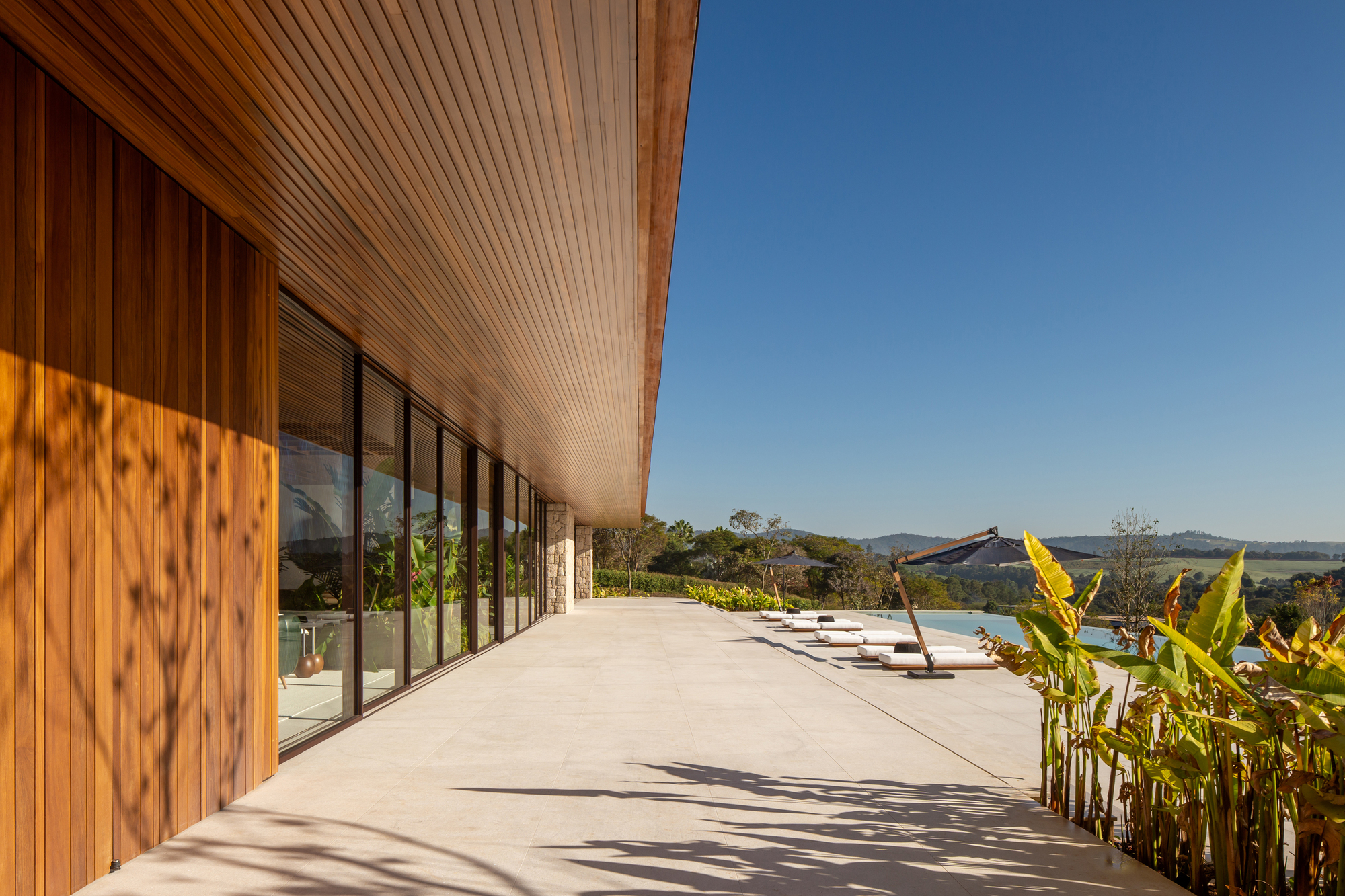 Wide covered terrace with stone paving and a timber slatted ceiling looking toward the surrounding countryside