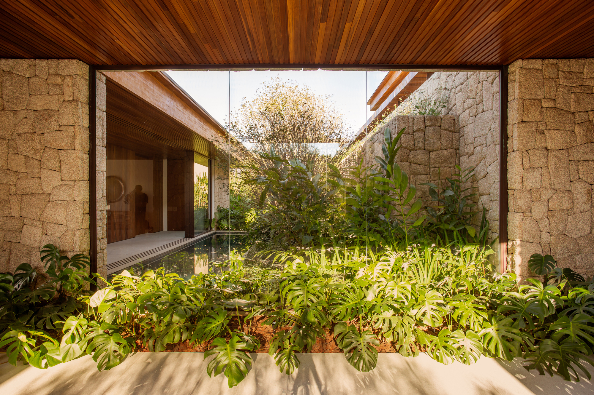Inner courtyard with rough stone walls and a small reflecting pool surrounded by tropical planting