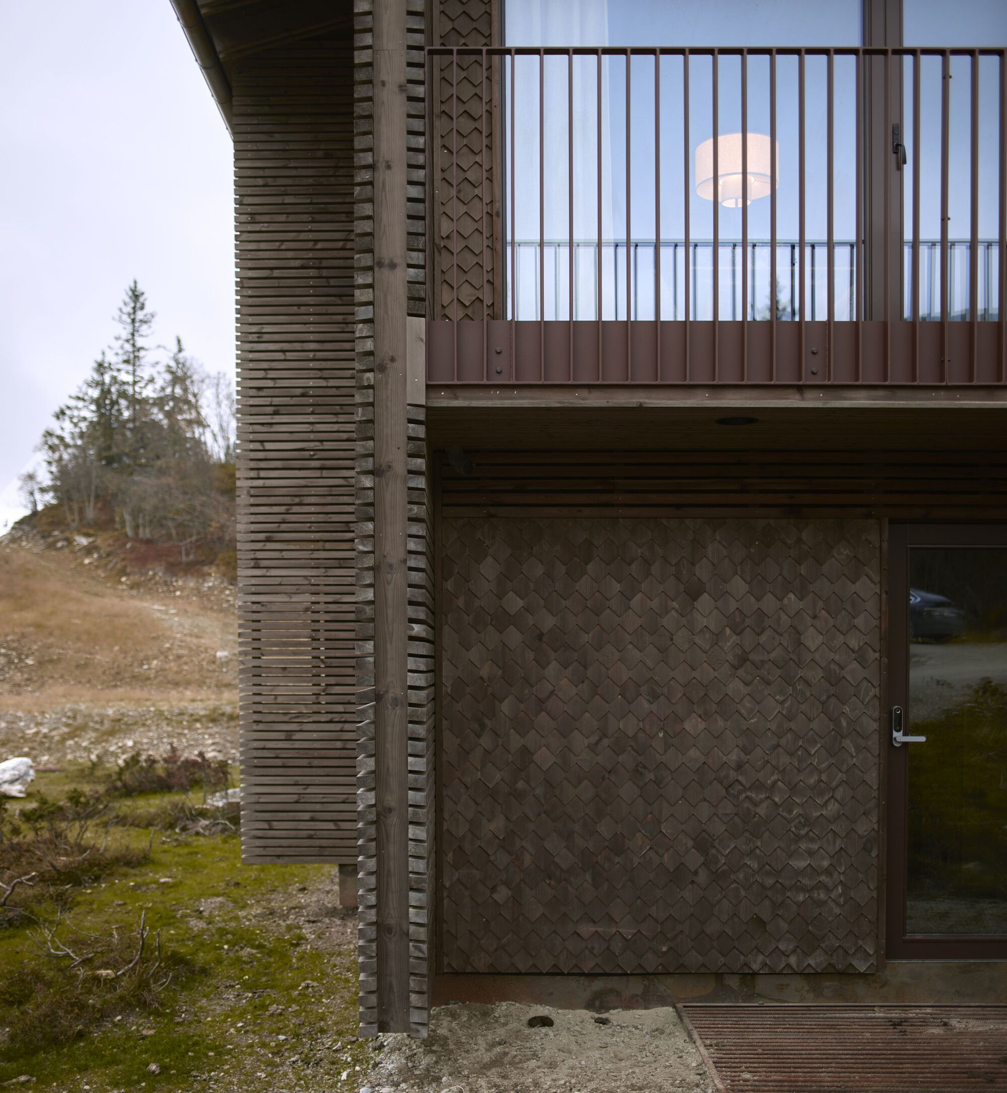 Cladding junction at the lower entry, balcony above, showing facade layers