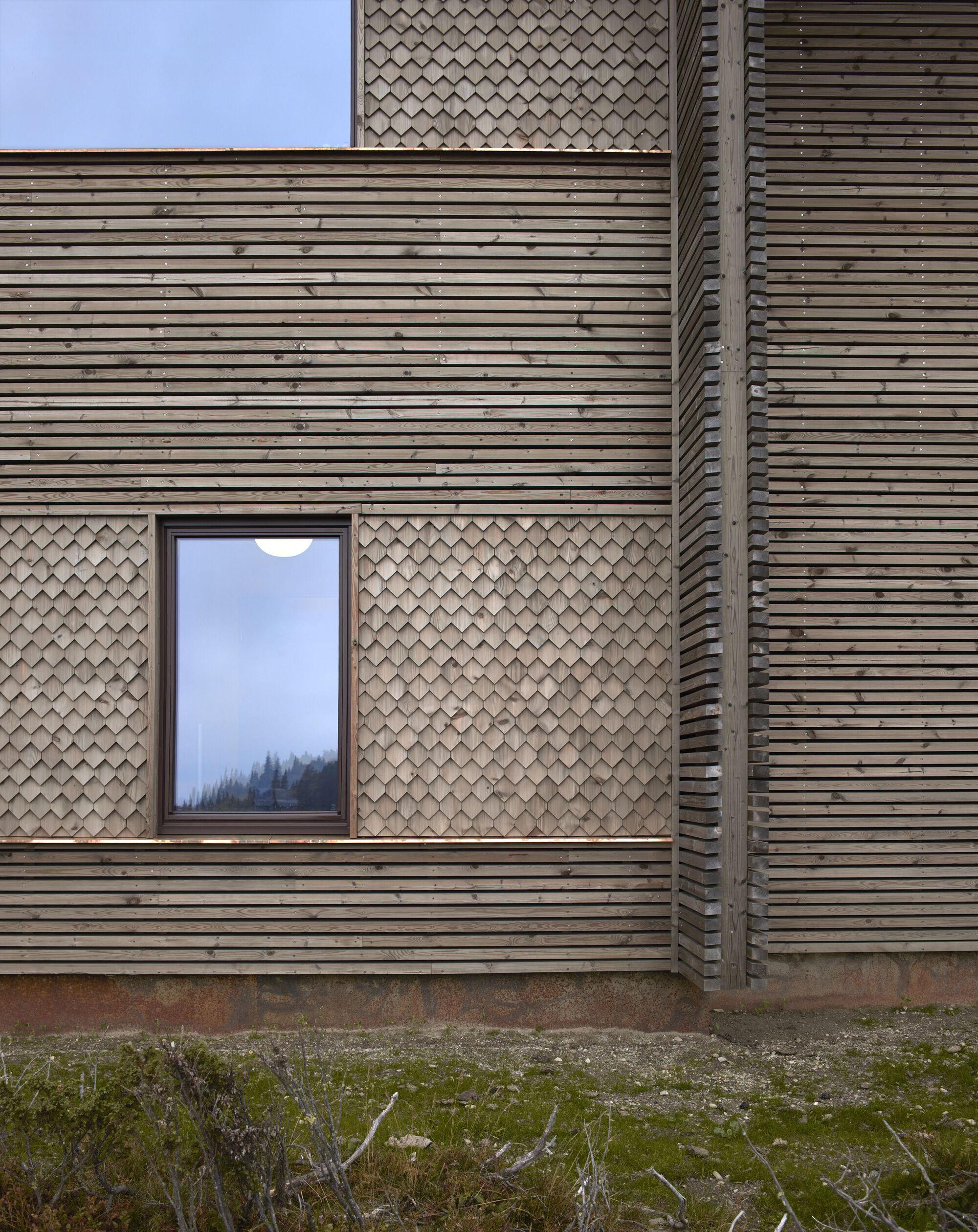 Horizontal cladding and diamond shingle panels framing a bedroom window