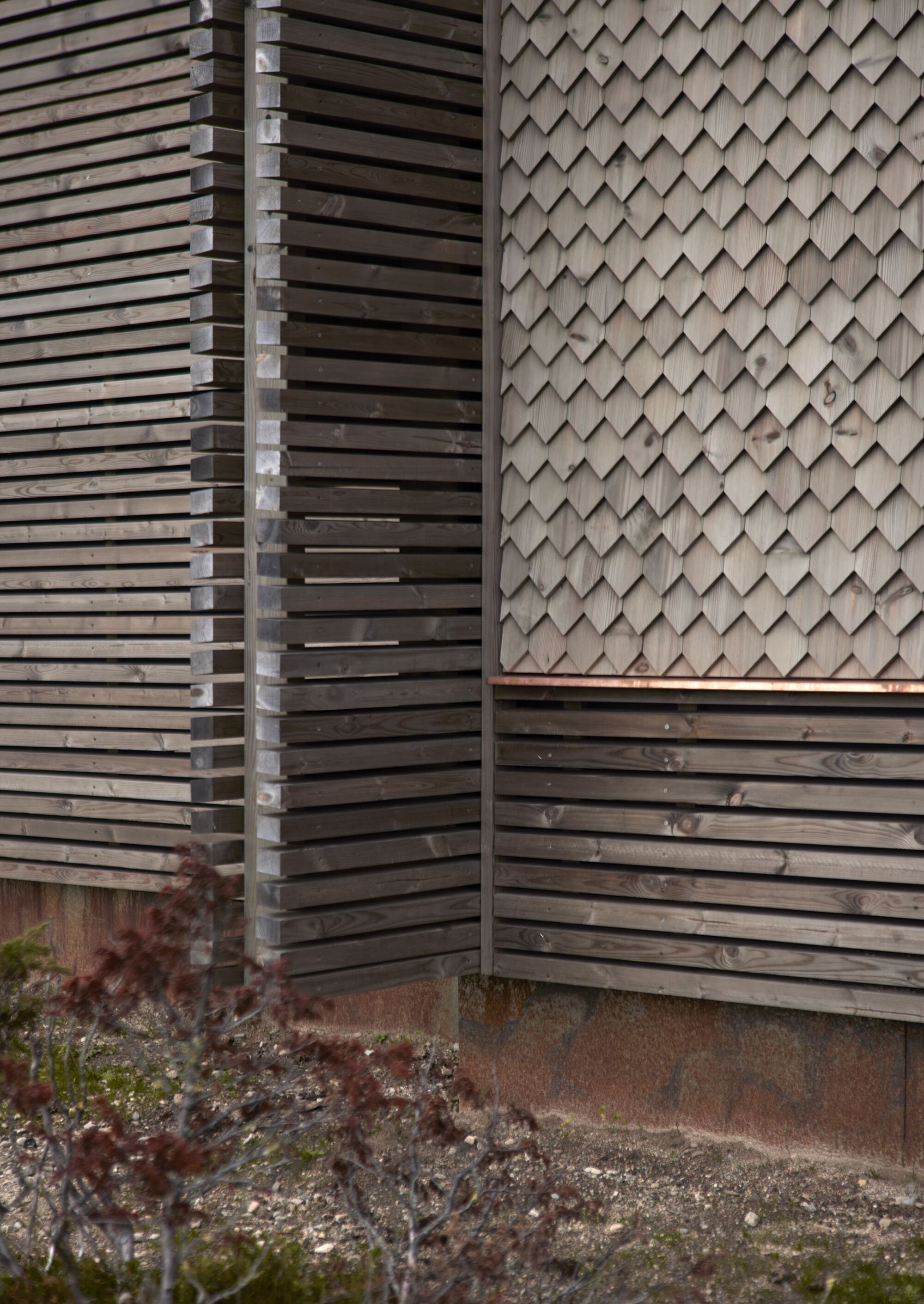 Close-up: junction of horizontal slats and diamond timber shingles with copper flashing