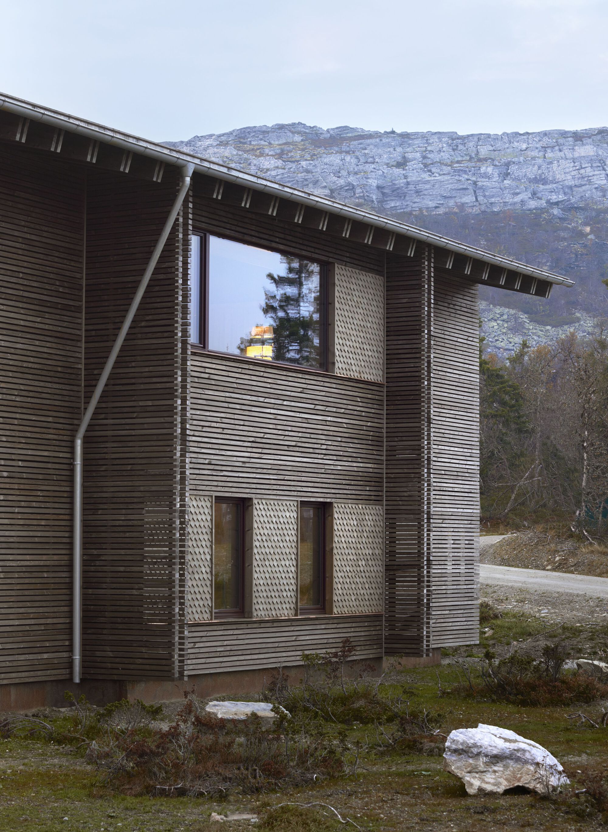 Side view: ventilated facade, deep overhang, and mountain backdrop