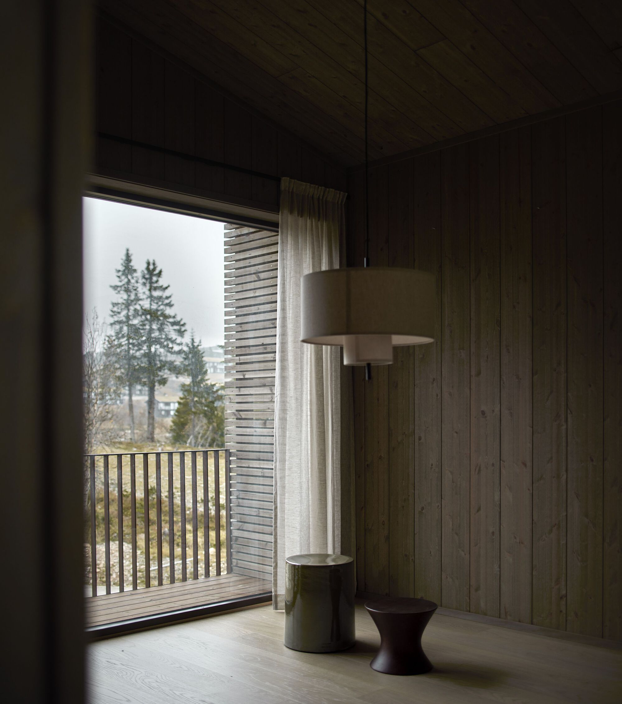 Bedroom corner: timber-lined walls, pendant lamp, balcony view through curtain