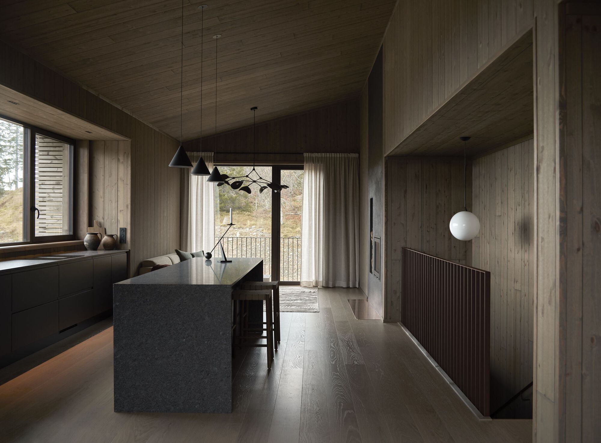 Open-plan kitchen, dining, and living room with dark stone island and panoramic mountain view